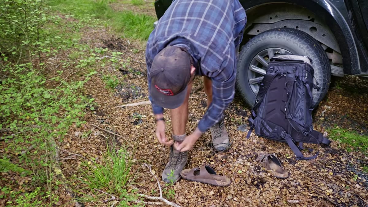 Patino lacing boots in field, golden light beginning to build