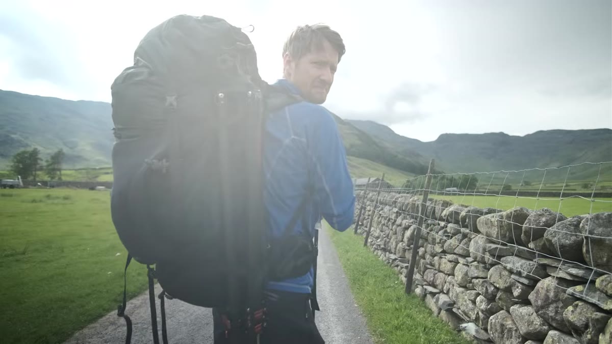 Thomas hiking uphill with visibly heavy pack on mountain trail
