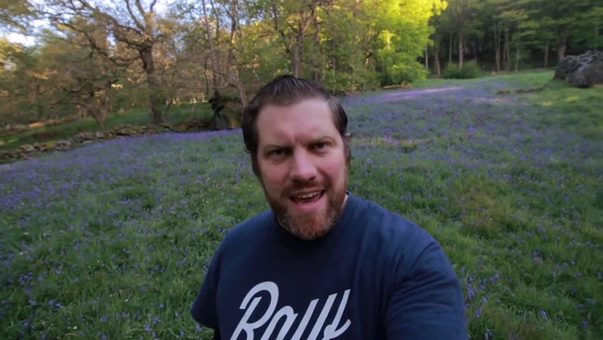 Photographer evaluating bluebell foreground against tree and rock background