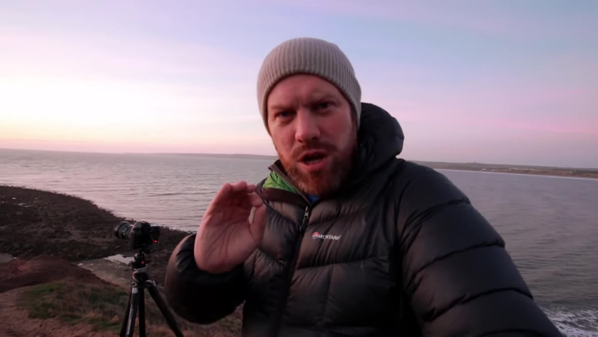 Photographer attaching ND filter to lens on tripod at headland