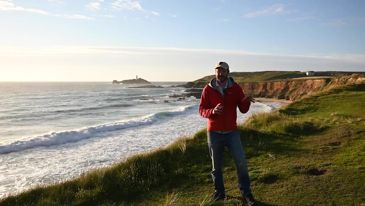 Danson walking along the clifftop scouting positions above the rocks