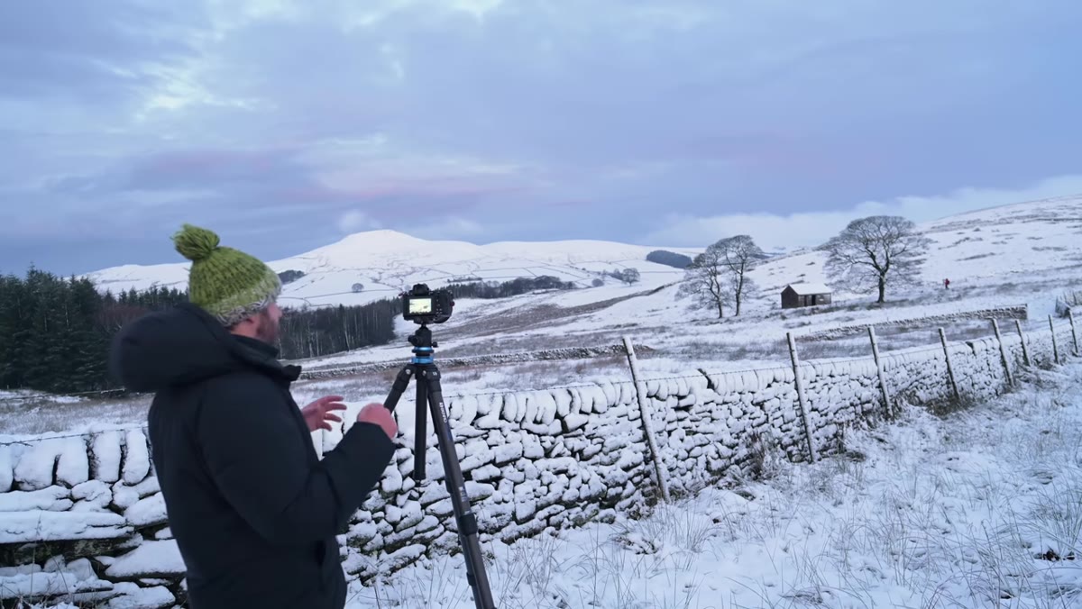 Wide shot showing white snow against dark stone walls and hillside