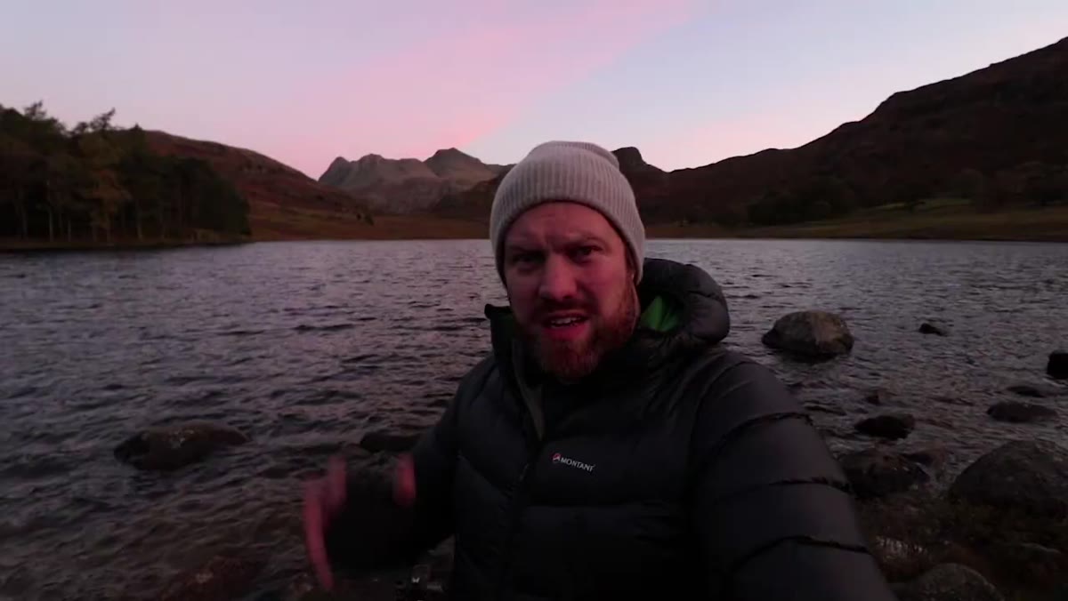 Photographer standing at Blea Tarn with pink sky visible behind him