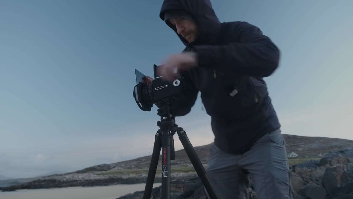Photographer setting polarizer and graduated ND filter over beach scene