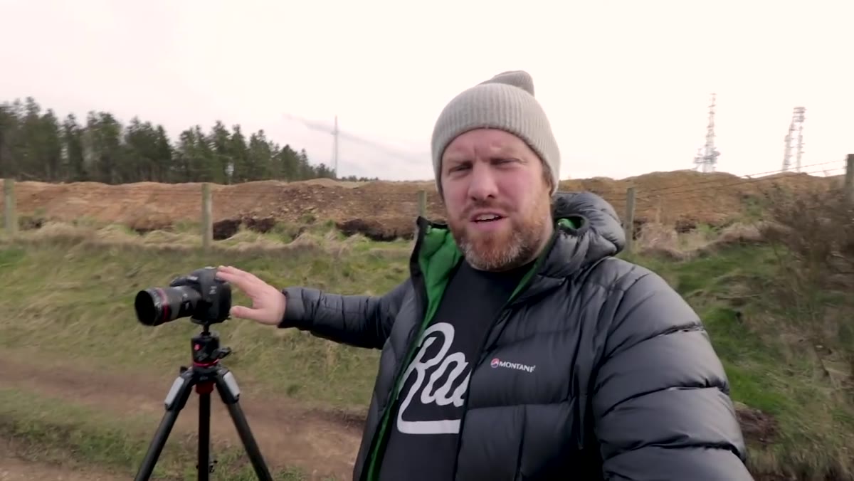 Photographer moving along hillside adjusting camera position for composition