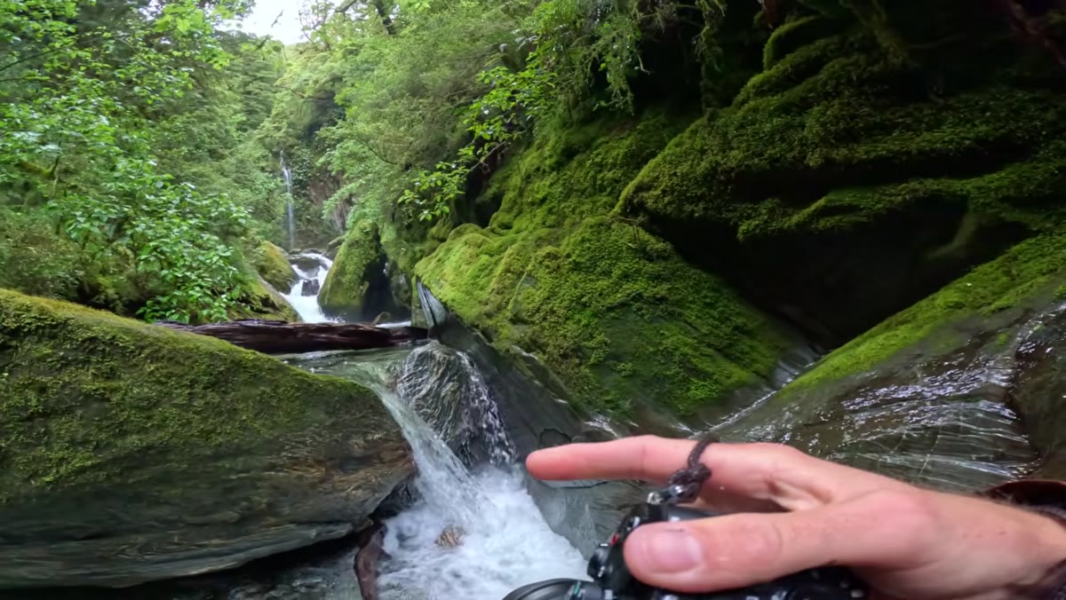 Wide foreground rocks, mid-ground cascade, background waterfall visible in gorge