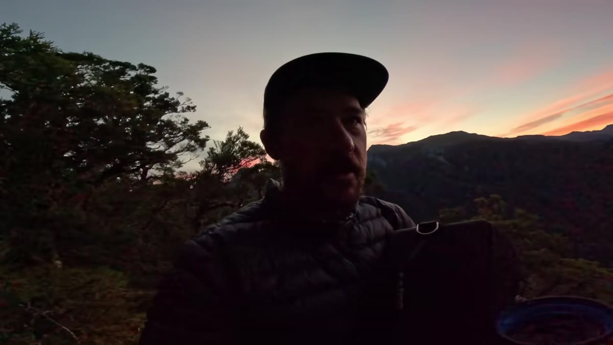 Photographer walking uphill toward a mountain viewpoint at dawn