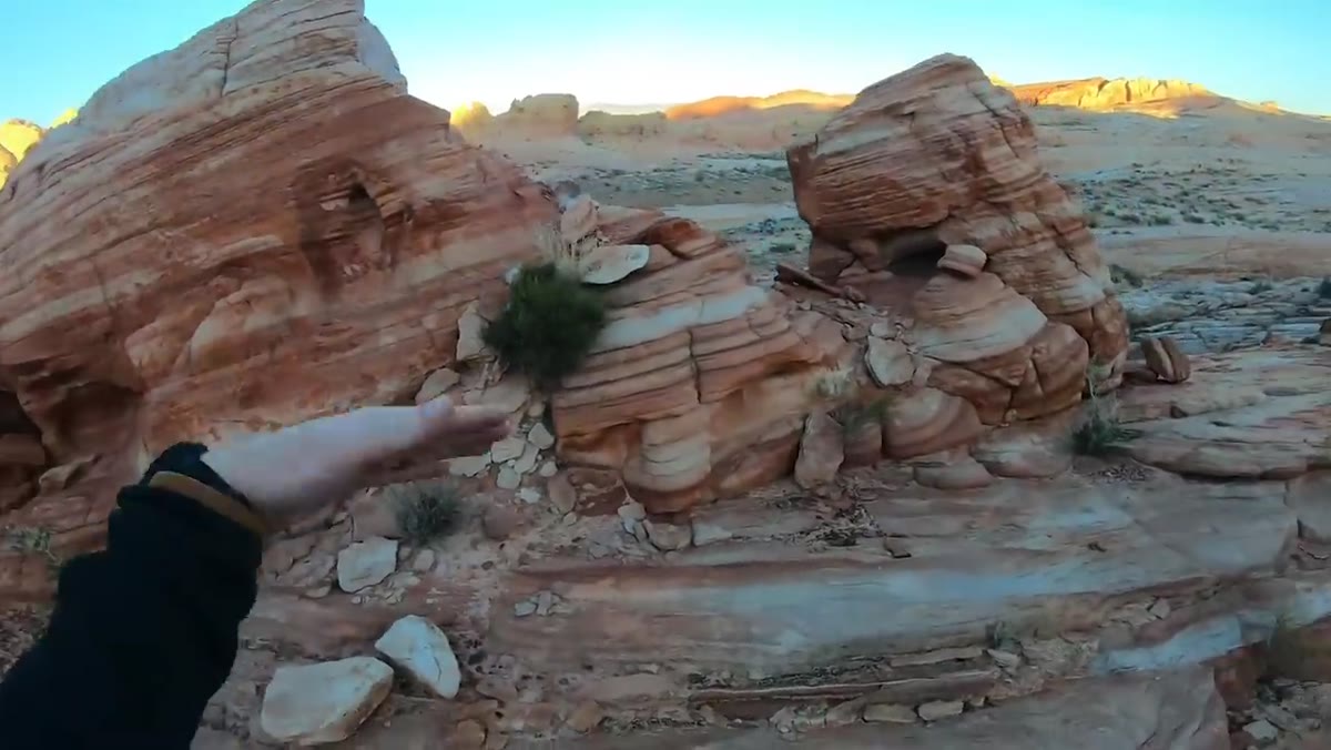 Heaton framing striped rock layers against distant lit hills