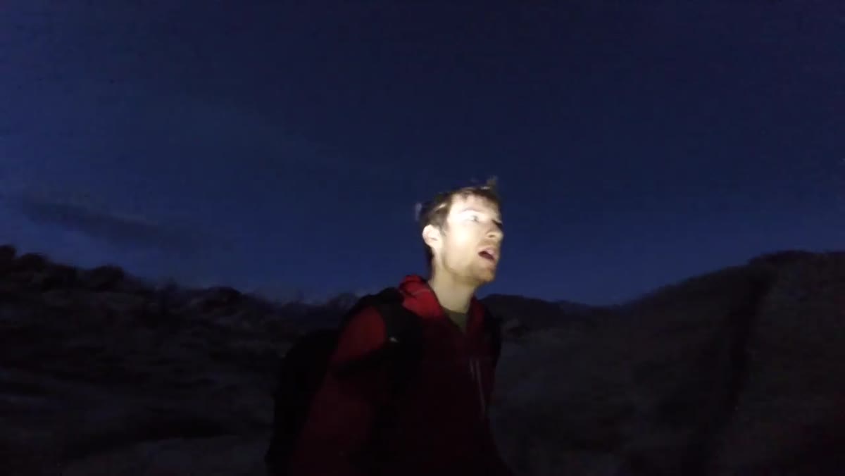 Heaton standing among large boulders in pre-dawn darkness