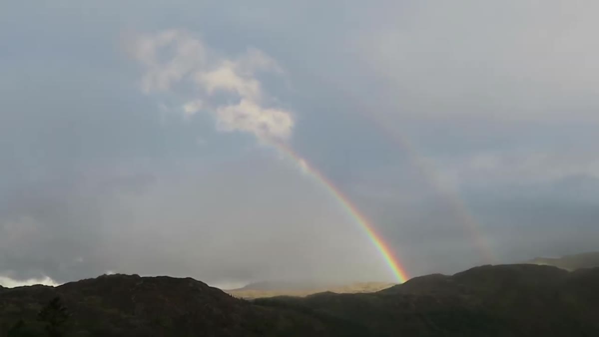 Rainbow appearing over the valley as sky begins to break