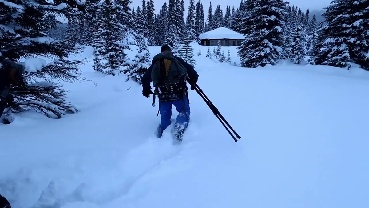 Photographers walking on knees through deep snow in single file