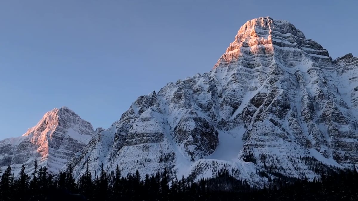 Mountain peak glowing pink-orange with alpenglow at sunrise