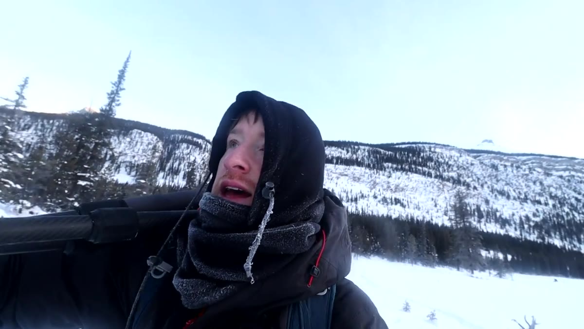 Thomas Heaton walking through deep snow toward frozen stream details