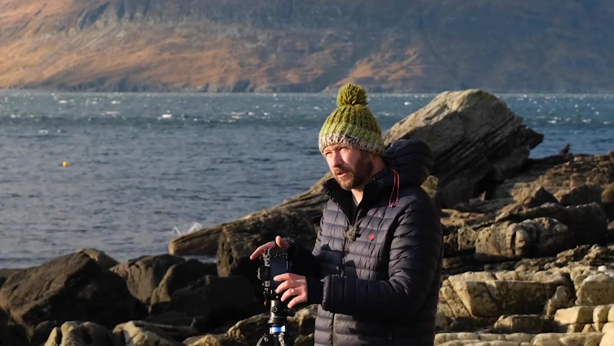 Nigel composing near water with rock in foreground, polarizer on lens