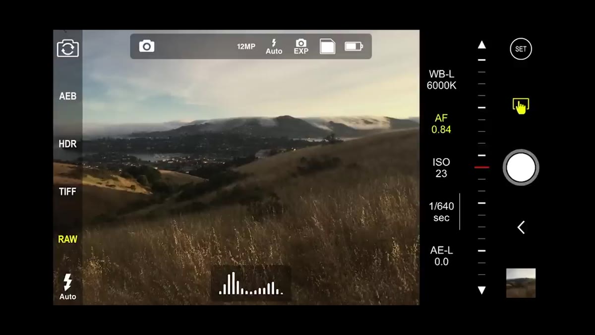 Finger adjusting exposure slider in ProCamera app on landscape scene