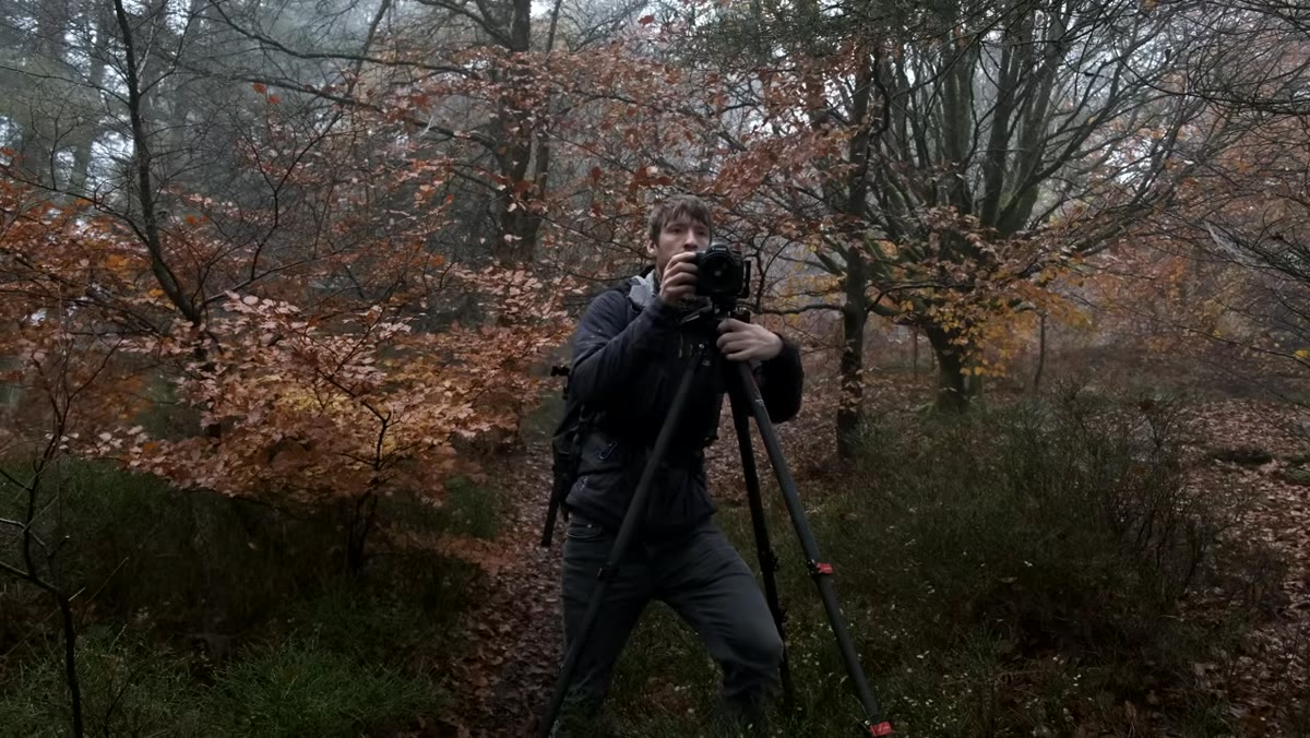 Heaton walking with camera and tripod over his shoulder