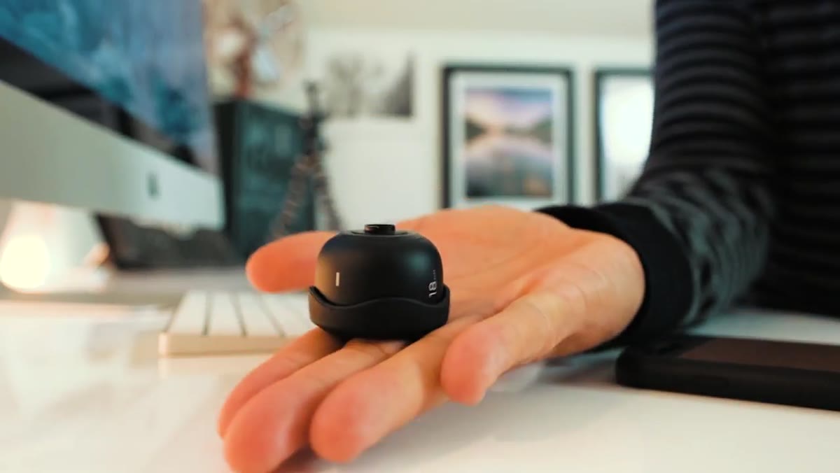Lens sitting in palm, showing compact size and metal construction