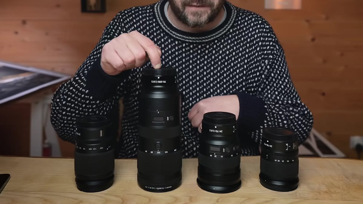 Danson holding two large lenses, comparing weight in hands
