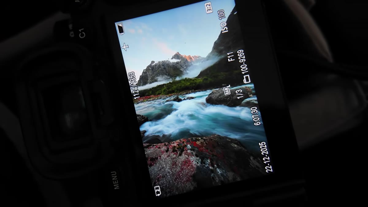 Photographer framing mountain peaks and river together in wide composition