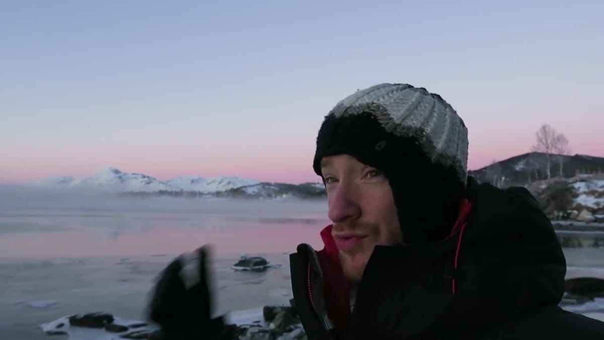 Thomas gesturing toward small rocky cove along fjord shoreline