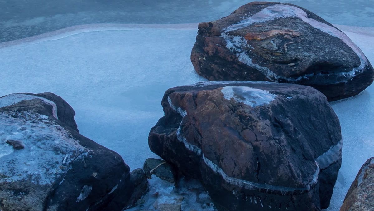 Camera mounted on tripod at rocky shoreline, polarizer attached