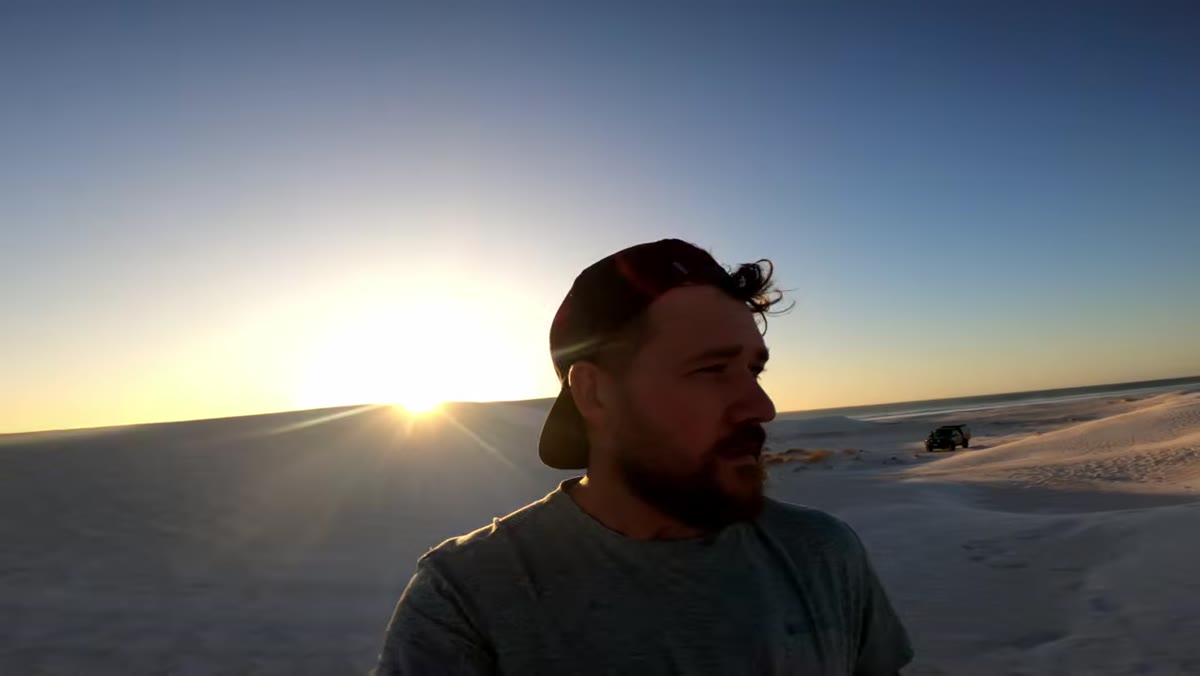 Photographer repositioning as light angle changes across dune surface