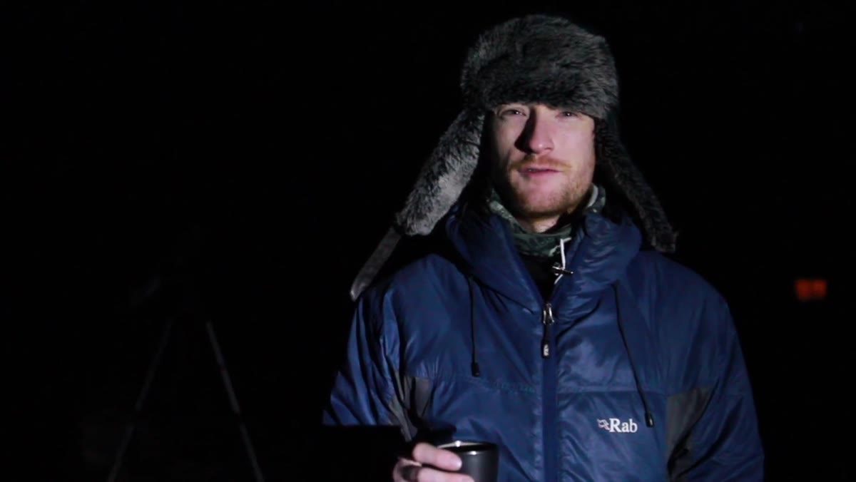 Thomas speaking to camera, nighttime coastal location visible behind him