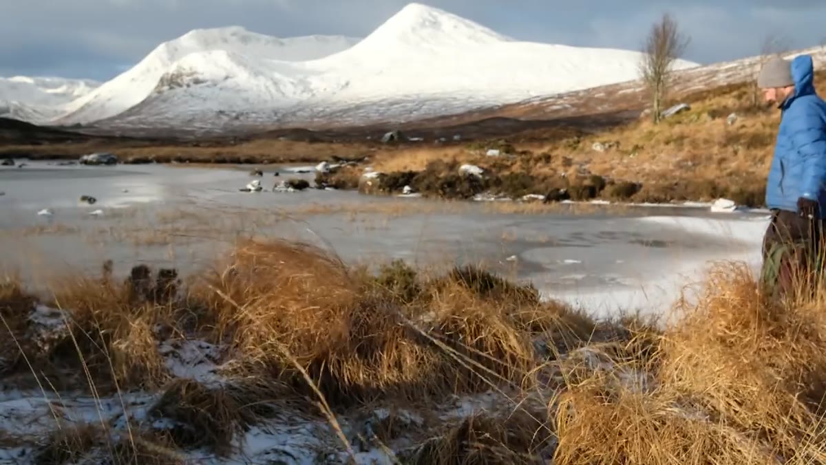 Frozen lake with crack in ice leading toward distant mountain