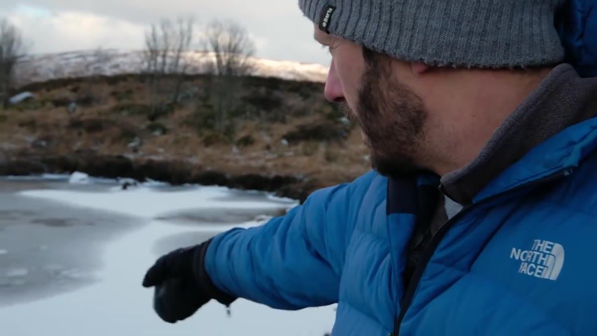Tripod set low near frozen lake with camera mounted