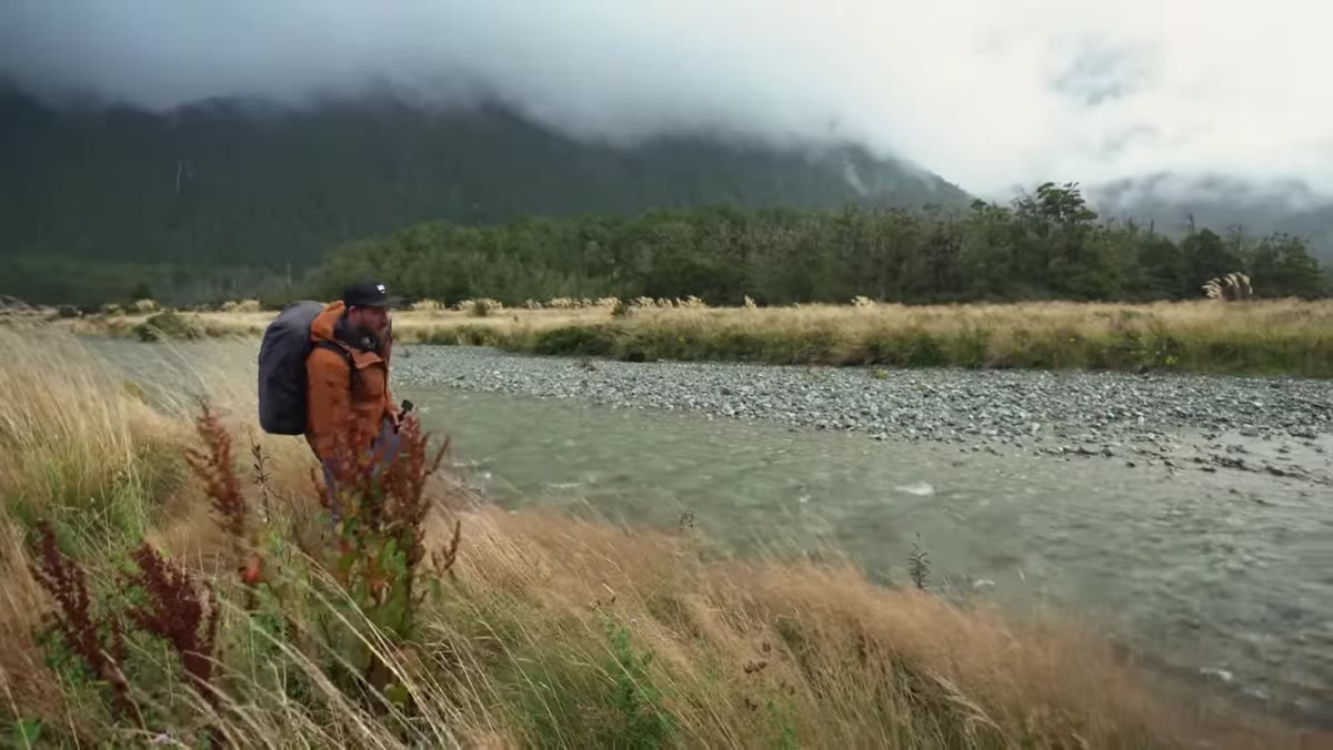 Patino wading through a river crossing with waders on