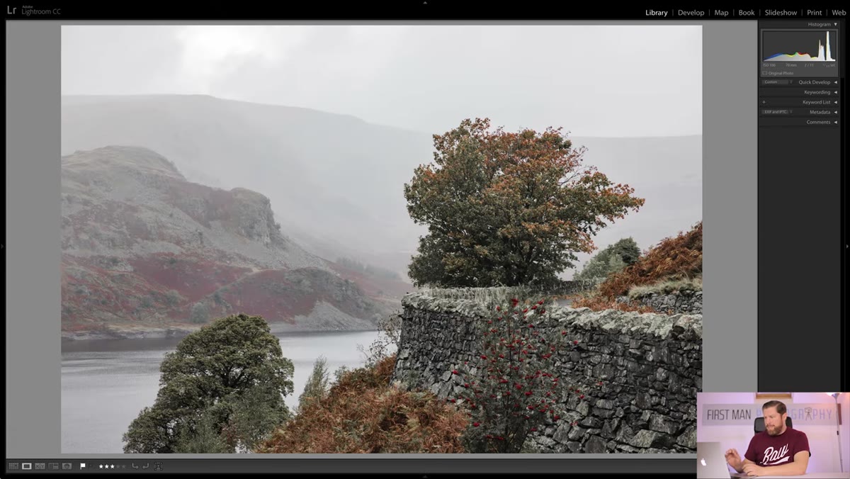 Curved stone wall leading toward lone tree and reservoir