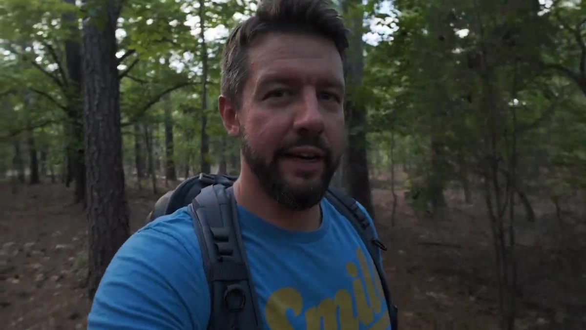 Photographer walking through woodland at dusk on a scouting mission