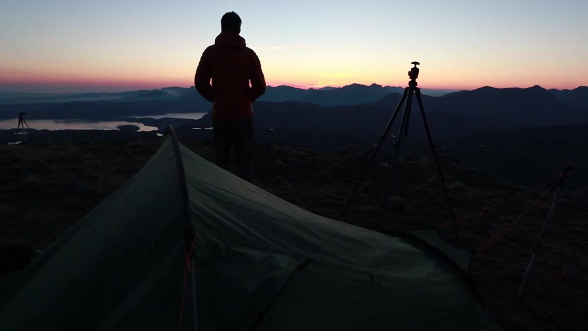 Photographer looking out from tent at still, hazy valley