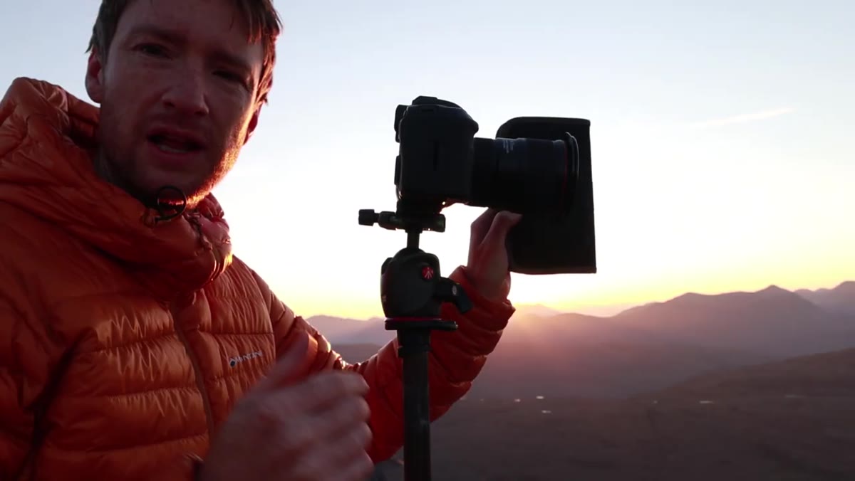 Photographer using hand to block sun flare from lens before shooting