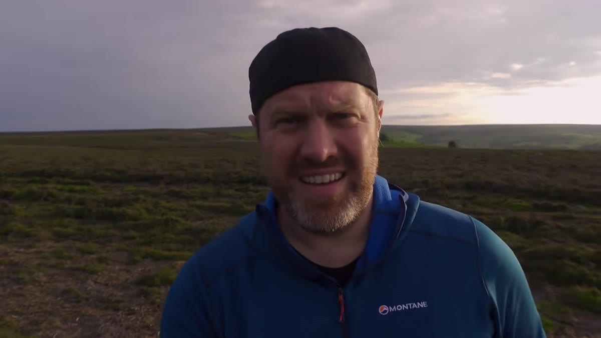 Adam standing near a lone tree on open moorland at golden hour