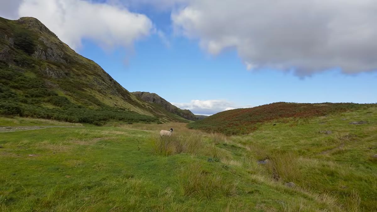 Wide shot of reclaimed quarry waterfall revealed through wire fence