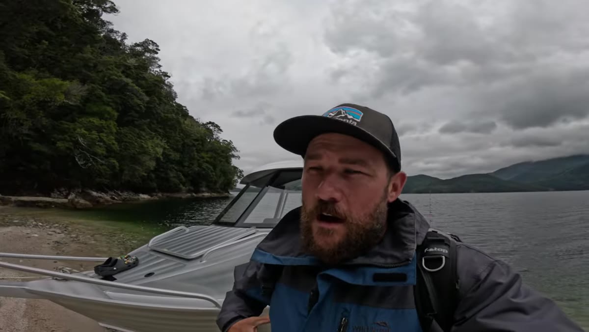 Photographer suited up in waders and wet weather gear at water&rsquo;s edge