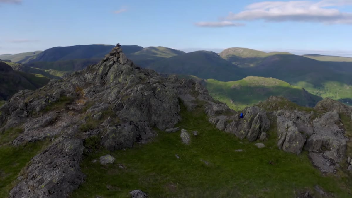Adam crouching behind low rock wall describing wind protection